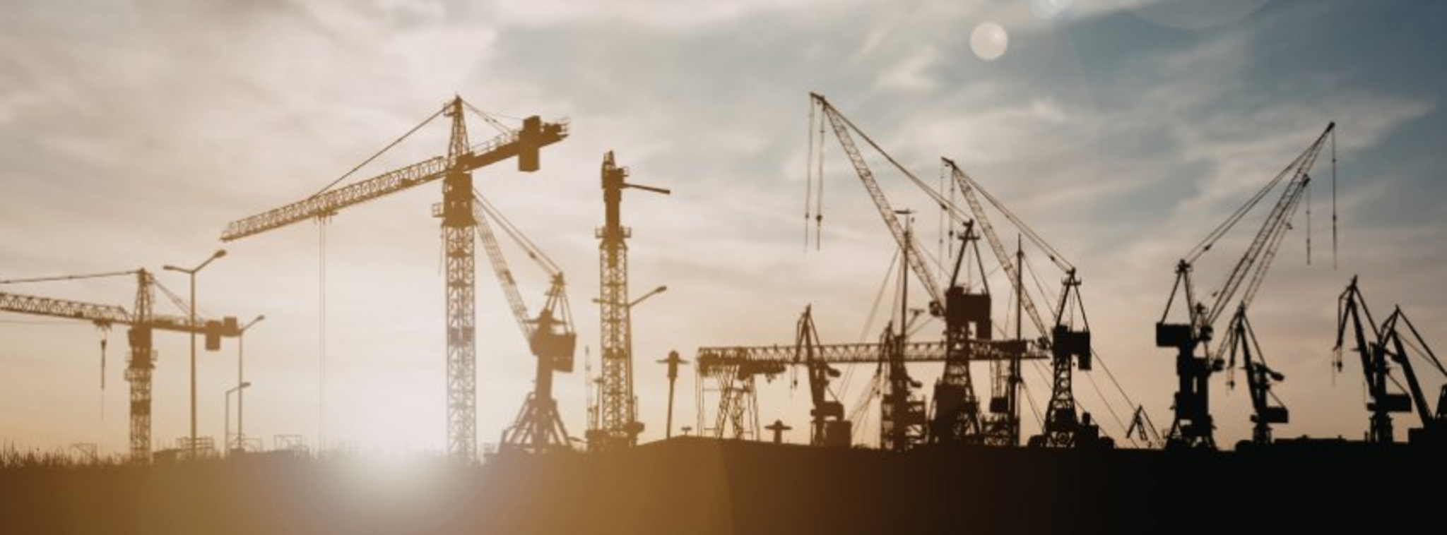 Construction cranes silhouetted at dusk